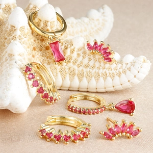 Vue détaillée de boucles d'oreilles dorées avec pierres fuchsia sur une étoile de mer et soie