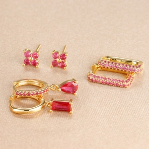 Détail d'un ensemble de trois boucles d'oreilles dorées avec cristaux roses et rubis