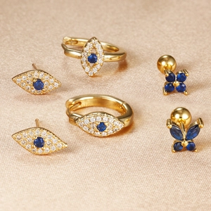 Detalle de pendientes de ojo turco dorados con cristales azules y tachuelas de flor