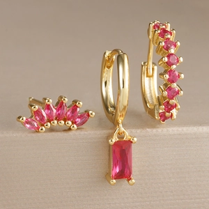 Détail macro de boucles d'oreilles dorées serties de zircons roses et rouges