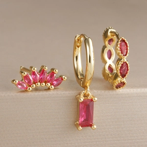 Détail d'un lot de trois boucles d'oreilles dorées serties de gemmes rouge foncé