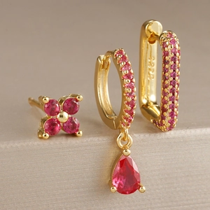 Gros plan du poinçon S925 sur boucles d'oreilles dorées avec breloques en zircon rouge