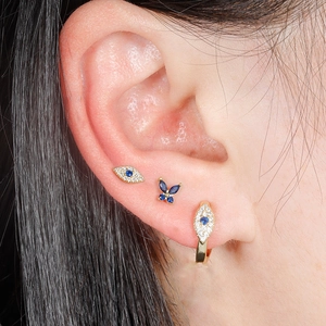 Set de 3 pendientes dorados de ojo turco y mariposa con piedras azules puestos
