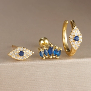 Primer plano del set de pendientes de ojo de la suerte dorados con detalles azules