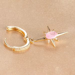 Macro shot of gold starburst earrings with pink gemstones on silk background