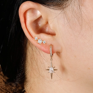 Close-up of gold star earrings with sparkling crystals worn by a model