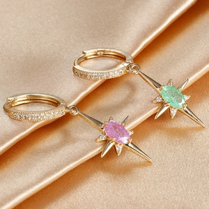 Macro detail of gold starburst earrings with pink and green oval stones on silk