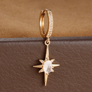 Macro detail of gold north star earrings with crystals on brown leather jewelry box