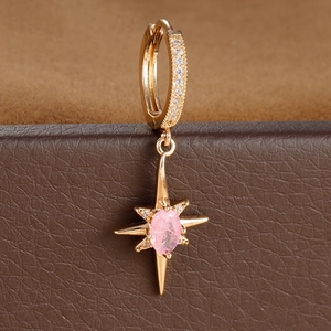 Macro shot of gold octagonal star earring with a pink gem and sparkling crystals