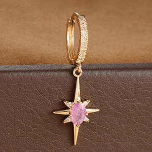 Macro shot of gold hoop earrings with pink oval stone and star pendant details