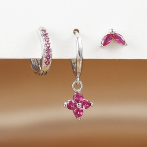 Detailopname van driedelige zilveren oorbellen set met magenta kristallen bloemen