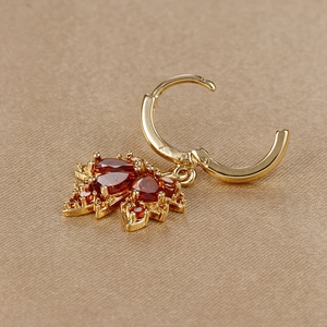 Makroaufnahme von Ahornblatt-Ohrringen mit Goldfinish und eingelegten roten Edelsteinen