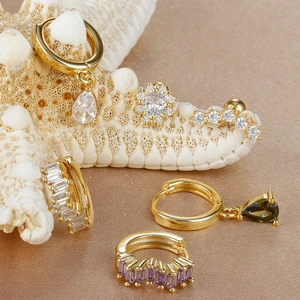 Detail von vergoldeten Ohrringen mit Zirkonia und Wassertropfen-Anhängern auf Seide