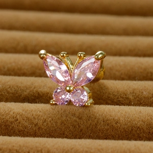 Macro view of golden butterfly ear stud featuring pink marquise-cut zircon stones