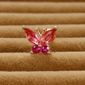 Macro view of gold butterfly ear stud with red and pink crystals on velvet