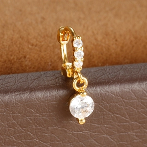Macro shot of gold-plated cartilage earring with micro-pave cubic zirconia on leather