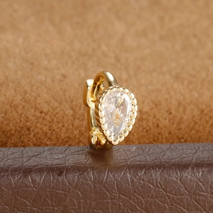Close-up of gold pear-cut cubic zirconia stud earring with milgrain detail and texture