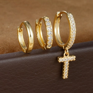 Detailweergave van gouden oorbellen met T-letterhanger en fonkelende zirkonia steentjes