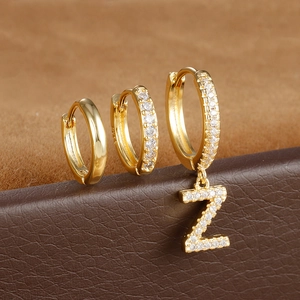 Detail met S925-keurmerk en fonkelende pavé-diamanten op gouden oorbellen met letterhanger
