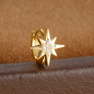 Macro shot of gold star-shaped ear cuff featuring inlaid cubic zirconia on leather base
