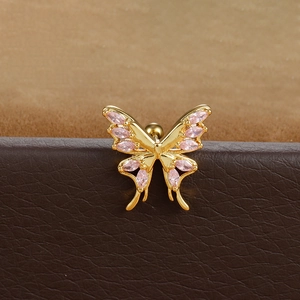 Detailed close-up of a golden butterfly ear stud with pink stones and a ball back screw