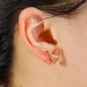 Macro shot of gold butterfly ear stud featuring sparkling pink marquise gemstones on ear