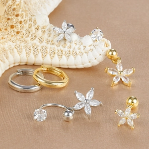 Dettaglio di un set di gioielli in oro e argento con fiori in zircone e cerchi su tessuto