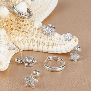 Dettaglio di un set di gioielli per piercing in argento e zirconi su seta e stella marina