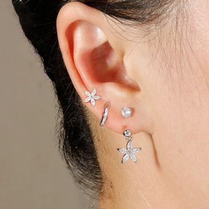Primo piano di orecchini a fiore in argento e zirconi indossati per dettagli