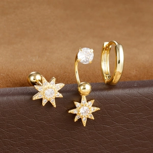 Dettaglio di orecchini dorati con stelle e zirconi su sfondo di pelle marrone con texture