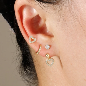 Dettaglio macro del set di orecchini placcati oro con cuori in zircone e cerchi sottili