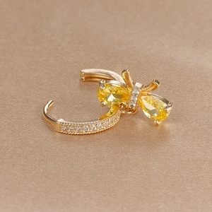 Close-up of golden bow earrings with yellow pear-shaped stones and pavé zircon accents