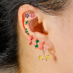 Micro shot of colorful cubic zirconia bow and floral earrings set on a golden base