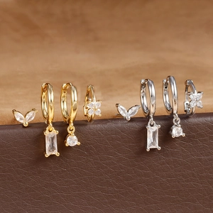 Detailed close-up of a 4-piece set of gold and silver zircon earrings on a leather stand