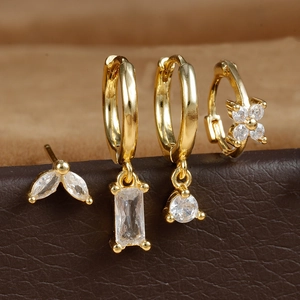 Set of 4 gold geometric earrings with marquise zircon and flower designs on leather display