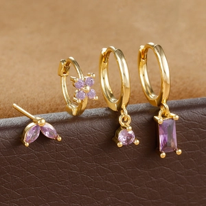 Detailed macro view of four-piece gold earring set with purple marquise zircons
