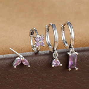 Close-up of four-piece silver earring set with purple marquise zircon and floral charms