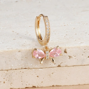 Detail of bowknot earring with pink pear-cut stones and zircon inlay on gold metal
