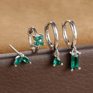 Detail of four-piece earring set featuring emerald green zircons on a leather display