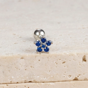 Detail shot of a silver flower ear stud with blue zircon petals on a textured stone base