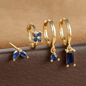 Detailed macro view of four-piece gold earring set with deep blue marquise-cut zircons