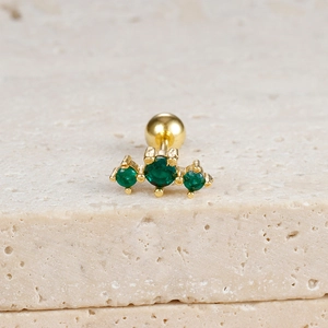 Macro shot of gold ear stud with three green zircons and screw-back ball closure