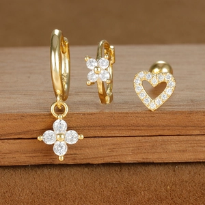 Detail of gold zircon jewelry set with flower and heart motifs on a wooden stand