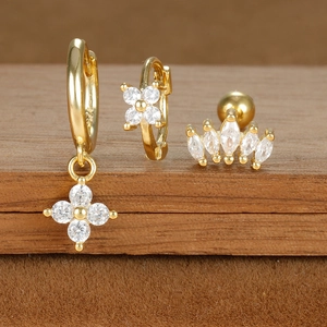 Macro view of S925 sterling silver gold clover earrings with micro-set zircons on wood