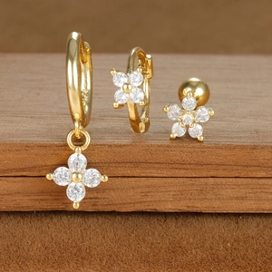 Macro detail of gold S925 silver earrings set with zircon star and flower charms