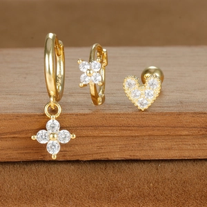 Macro shot of 18K gold plated earring set with zircon stars and hearts on wood