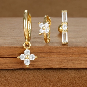 Detailed view of three-piece gold-plated zircon star and moon earring set on a wooden stand
