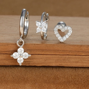 Detail of silver earrings set featuring flower pendants and hollow heart stud with white zircons