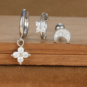 Macro shot of a three-piece jewelry set featuring star, moon, and flower zircon earrings