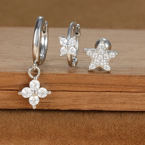 Detailed close-up of silver-tone star and floral earrings set with cubic zirconia stones